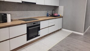 A modern kitchen with white cabinets, a wooden countertop, a built-in oven, and a sink.