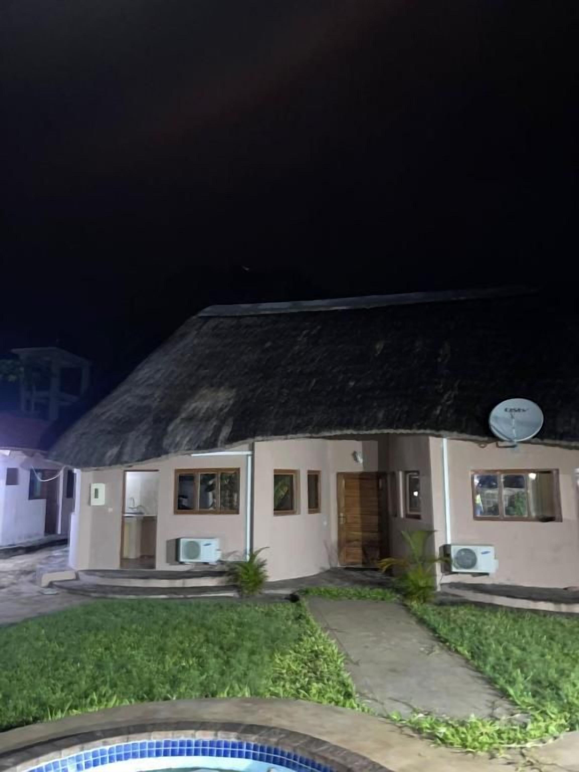 A building with a thatched roof, satellite dish, and outdoor air conditioning units.