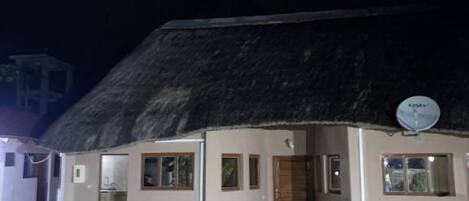 A building with a thatched roof, satellite dish, and outdoor air conditioning units.