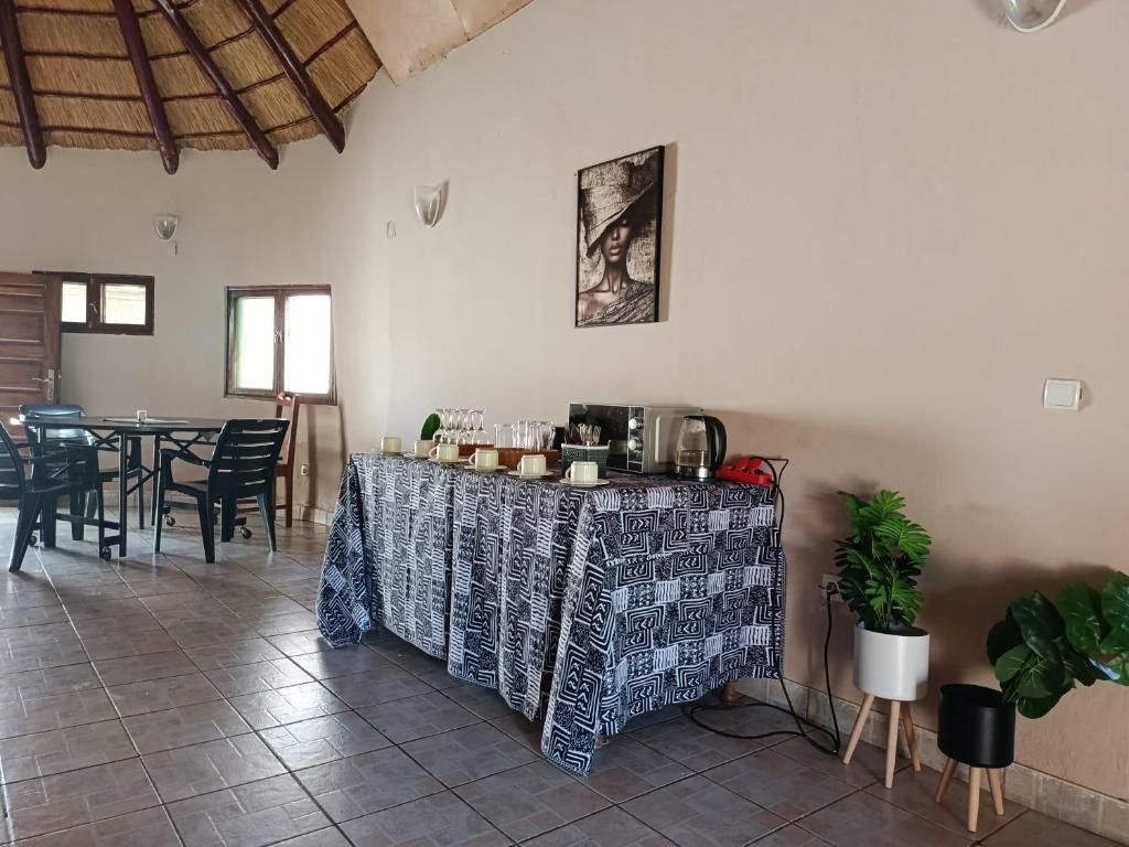 A dining area with a table set for four, a coffee machine, and a painting on the wall.