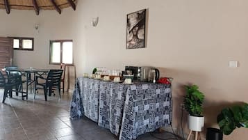 Un comedor con una mesa preparada para cuatro personas, una cafetera y un cuadro en la pared.