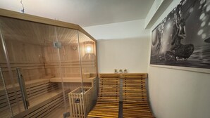 Uma sala de sauna com bancos de madeira, um compartimento de vidro e aquecedor fixado na parede.