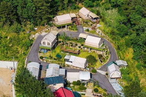 An aerial view of a campsite with multiple tents and cabins, surrounded by dense forest.