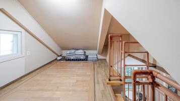 Un amplio ático con piso de madera, una escalera con barandilla de metal y un tragaluz.