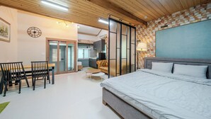 A bedroom with a large bed, a dining area with chairs, a kitchen, and a living area with a sofa. - Pocheon Terrace 527 Campground (Pocheon)