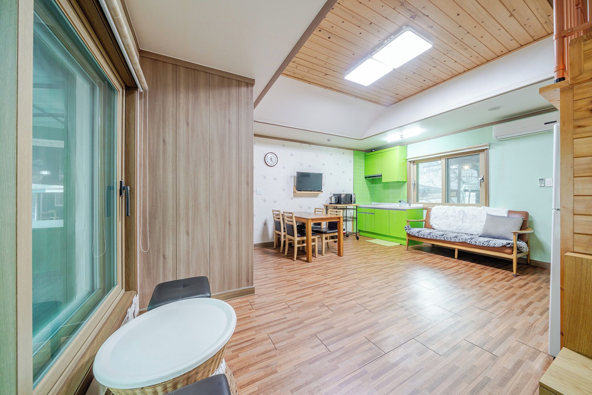 A compact living space with a dining area, kitchenette, and a sofa.