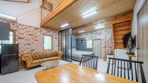 A compact living space with a kitchenette, a sofa, a dining table, and a bedroom with a bed and a window. - Pocheon Terrace 527 Campground (Pocheon)