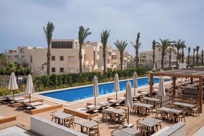A rooftop pool area with lounge chairs, umbrellas, and tables. - Casa White (El Alamein)
