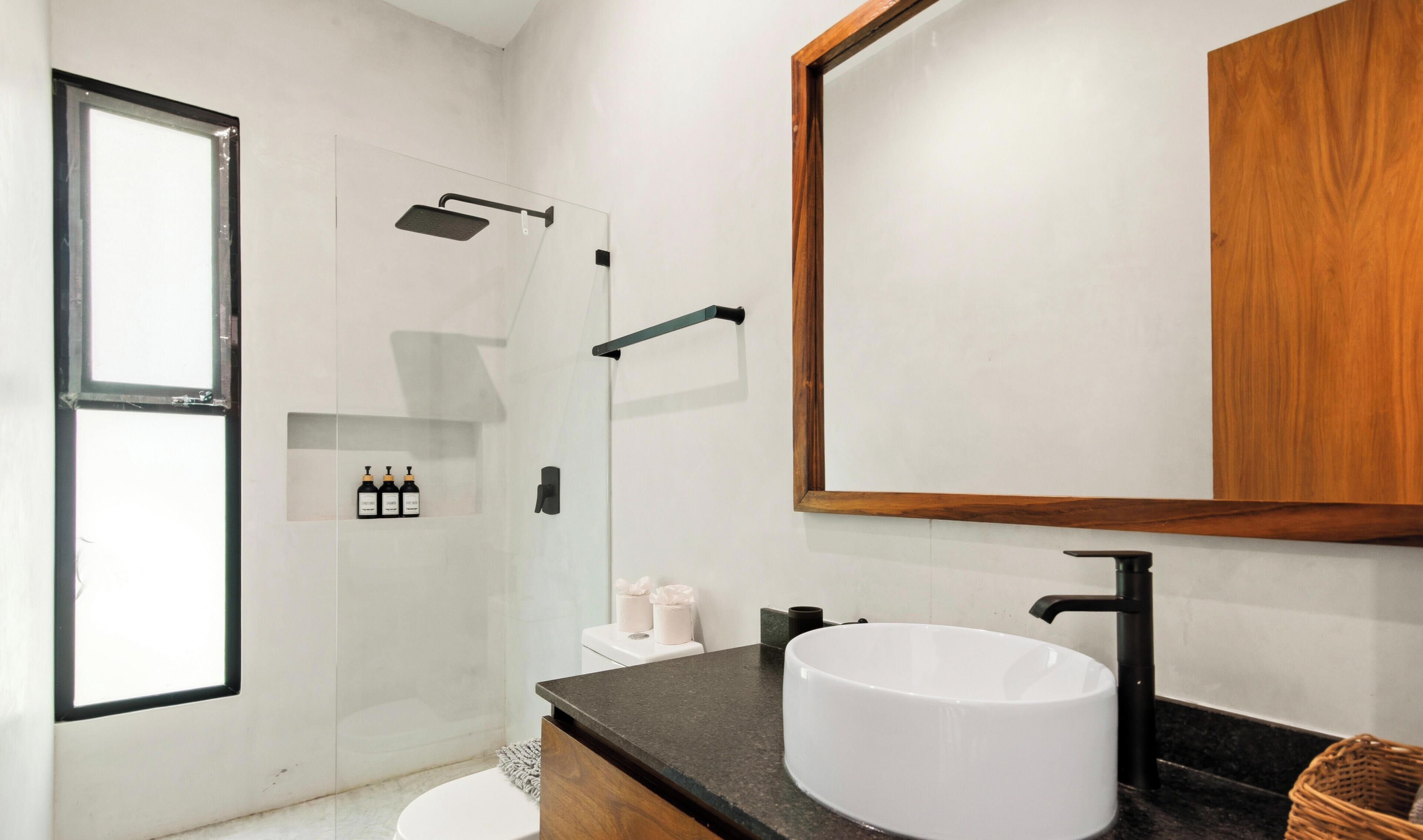 A modern bathroom with a freestanding bathtub, a large mirror, and a toilet.