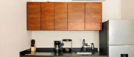 A kitchen with wooden cabinets, a stainless steel refrigerator, a coffee maker, and a sink.