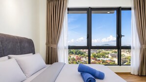 A hotel room with a bed, curtains, and a large window with a city view. - Chic 2BR Stay by Jonker Street (Malacca City)