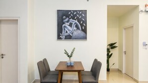 A room with a dining table, two chairs, a painting on the wall, and a potted plant. - Chic 2BR Stay by Jonker Street (Malacca City)