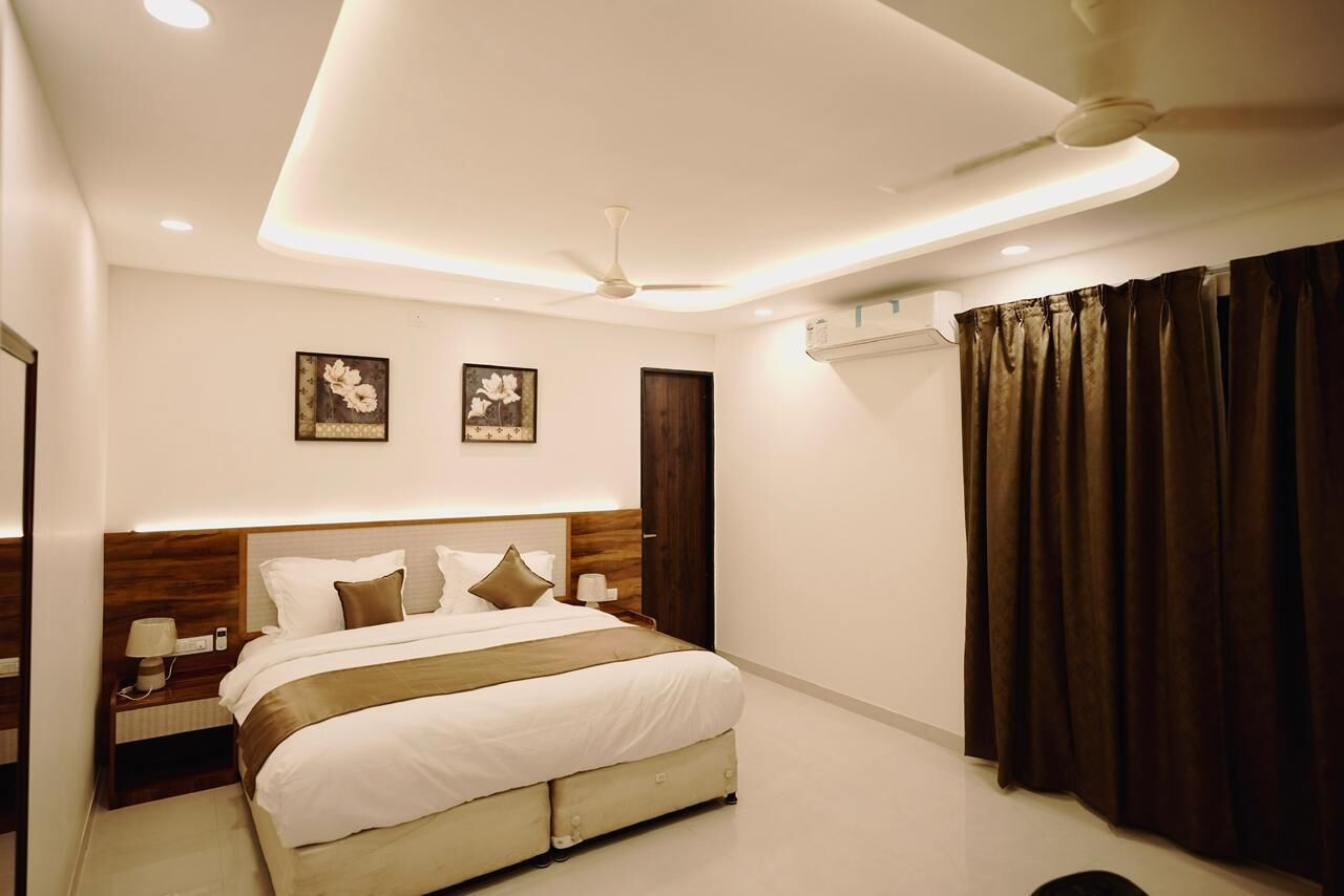 Um quarto de hotel moderno com uma cama grande, mesas de cabeceira, ventilador de teto e obras de arte na parede.