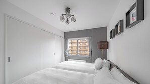 A bedroom with a bed, a window with curtains, a wall-mounted lamp, and framed pictures. - MEDIOFLAM 503 (Sapporo)