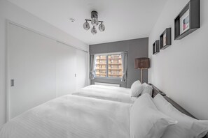 A bedroom with a bed, a window with curtains, a wall-mounted lamp, and framed pictures. - MEDIOFLAM 503 (Sapporo)