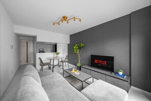A modern living room with a sofa, coffee table, and a flat-screen TV mounted on a grey wall. - MEDIOFLAM 503 (Sapporo)
