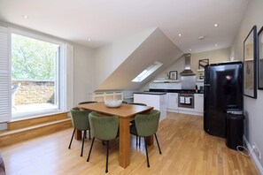 A modern kitchen with a dining area, a black refrigerator, and a skylight. - The Eaves on Santos Road (London)