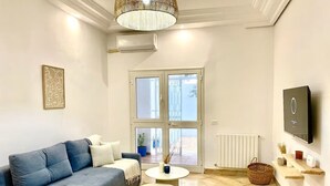 En moderne stue med en sofa, to sofaborde, et fjernsyn og et stort vindue.