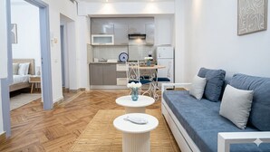 En moderne stue med sofa, spisebord og et køkken i baggrunden.