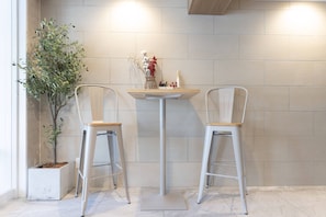 A corner with two white metal chairs, a small table with a vase and decorative items, and a potted plant. - b&Hanazono2 (Bainan, Nishinari Ward,)