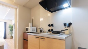 A compact kitchen with a microwave, stove, and utensils. - b&Hanazono2 (Bainan, Nishinari Ward,)