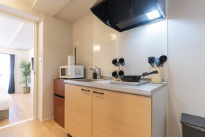 A compact kitchen with a microwave, stove, and utensils. - b&Hanazono2 (Bainan, Nishinari Ward,)