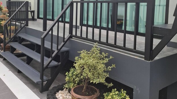 Un edificio moderno con una zona esterna coperta, una scala e piante in vaso.