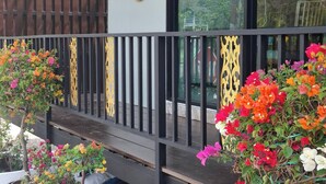 Un ristorante con un cartello, posti a sedere all'aperto con ringhiera e piante in vaso.