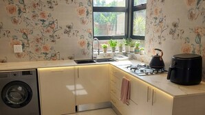 Eine moderne Küche mit Waschmaschine, Gasherd und einem Fenster mit Blick auf Grünflächen.