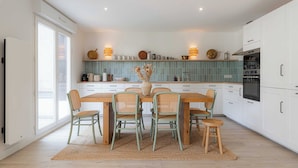 A modern kitchen with white cabinets, a wooden dining table, and four chairs. - Magnificent Apartment - 2br- 6P - Garden - Deauville (Deauville)