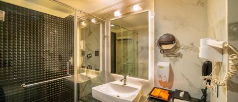 A modern bathroom with a glass shower enclosure, a white sink, and a large mirror.