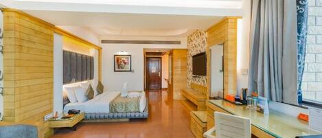 A hotel room with a bed, desk, chair, and a large window with curtains.