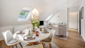 A modern, well-lit dining area with a round table, white chairs, and a ceiling fan. - Nordic Stay Bäk: Private Terrace & Garden near Lake Ratzeburg, Lübeck, Mölln (Bäk)