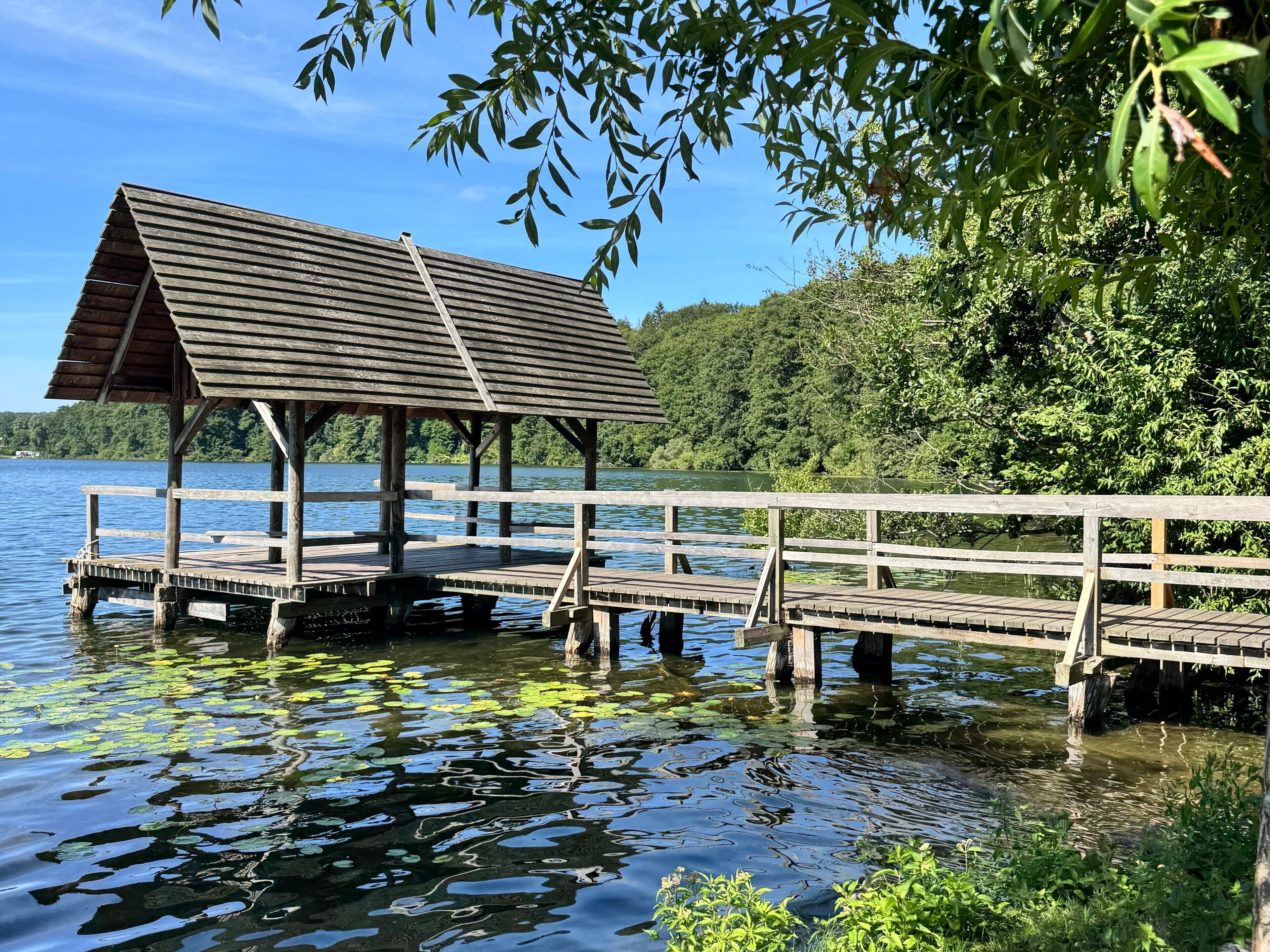 Une jetée en bois s’avançant dans un lac, avec un pavillon abrité.