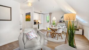 A modern interior with a dining area, kitchen, and a loft bedroom with a skylight. - Nordic Stay Bäk: Private Terrace & Garden near Lake Ratzeburg, Lübeck, Mölln (Bäk)