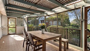A covered patio with a table and chairs, large windows, and a view of the outdoors. - 
Country on the Coast (Numbaa)