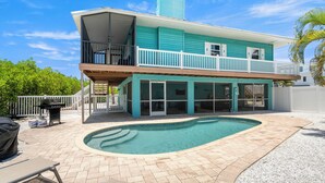 Ein zweistöckiges Haus mit Swimmingpool, Balkon und überdachter Terrasse.
