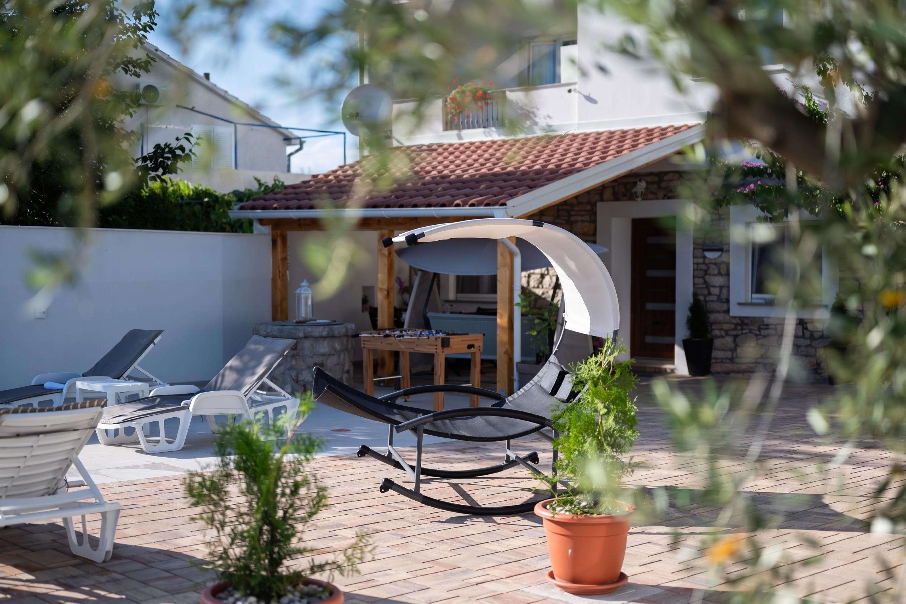 A patio with lounge chairs, a foosball table, and a pergola.