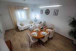 A dining area with a round table set for four, a sofa, a floor lamp, and a potted plant. - Pool House Ivana (Novigrad)