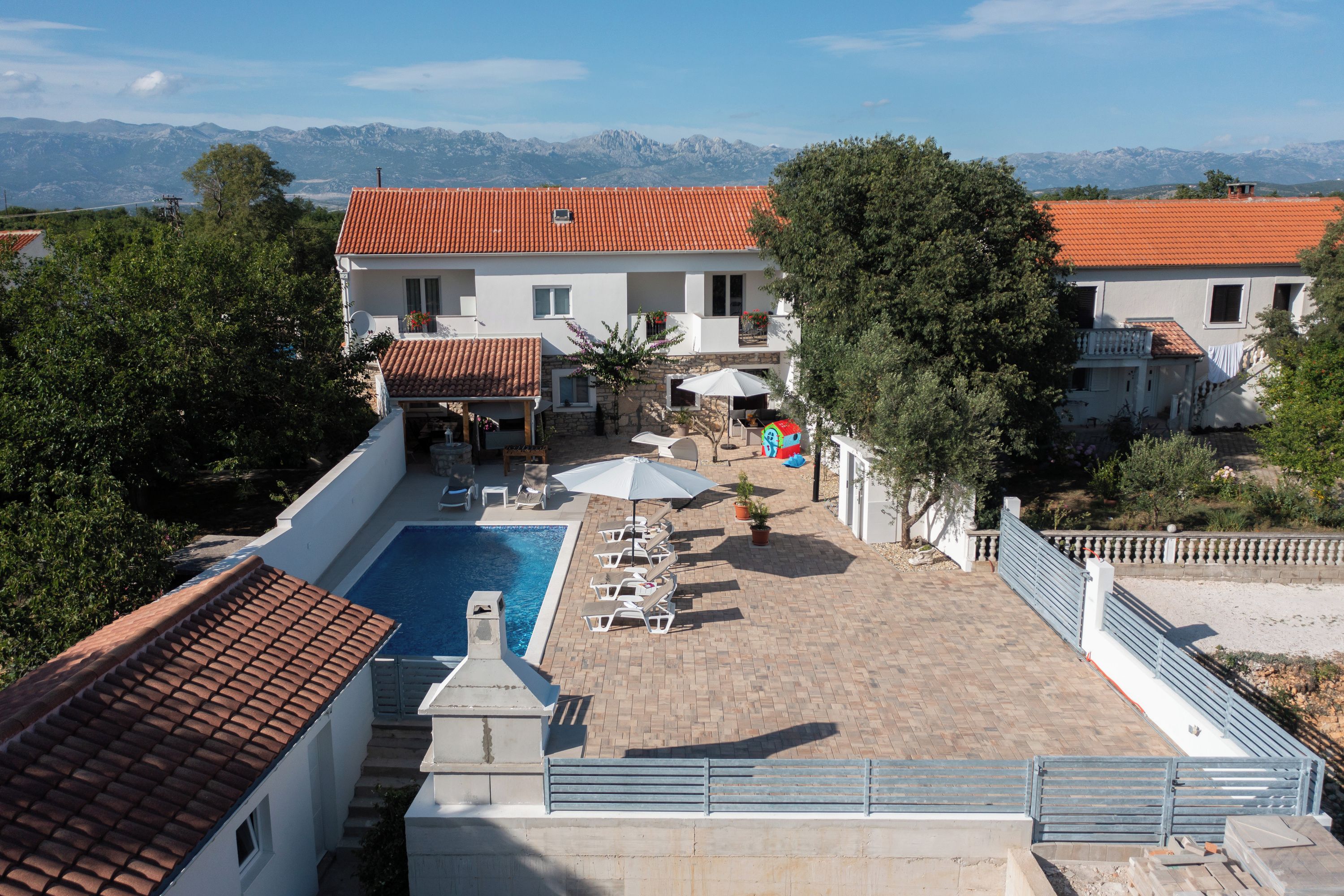 A villa with a swimming pool, outdoor seating, and a view of mountains.