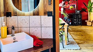 Ein Badezimmer mit einem Holzkosmetikschrank, einem weißen Waschbecken, einem Spiegel und einem roten Handtuch.