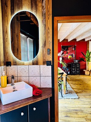 A bathroom with a wooden vanity, a white sink, a mirror, and a red towel. - La Maison Rouge Riquewihr (Riquewihr)