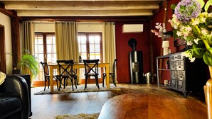 Ein Zimmer mit Holzboden, einem Esstisch mit Stühlen, einer Couch, einem Kamin und einem Schrank mit Dekoration.