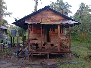 A rustic wooden structure with a corrugated metal roof, surrounded by lush greenery.