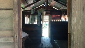 A wooden interior with a high ceiling, a bench, and hanging laundry.