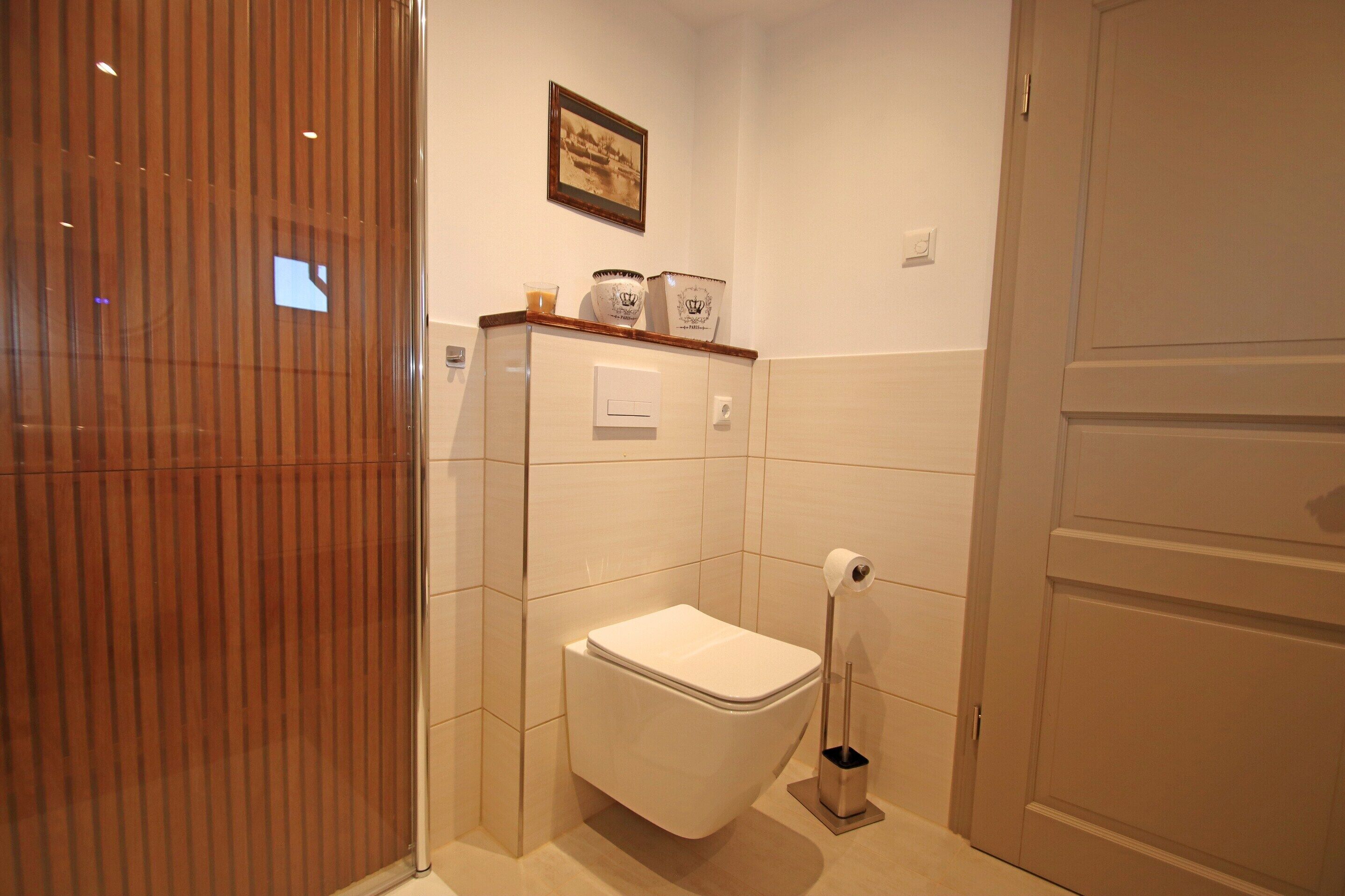 A bathroom with a toilet, a bidet, a towel rack, and a framed picture on the wall.