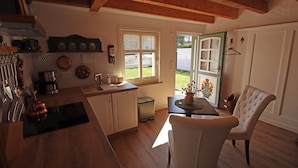 Una cocina con armarios de madera, un lavamanos y una zona de comedor con mesa y sillas.