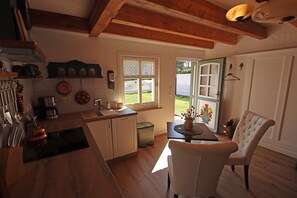 A kitchen with wooden cabinets, a sink, and a dining area with a table and chairs. - Ferienhaushalfte Schusters Kate in Zempin (Zempin)