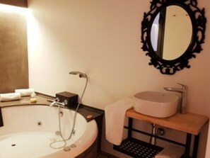 A bathroom with a bathtub, a sink, a mirror, and a towel rack. - Deluxe Apartment With Jacuzzy (Alicante)