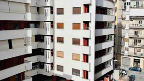 Un immeuble résidentiel à plusieurs étages, doté de balcons, d’un espace de stationnement et surplombant un ciel dégagé.